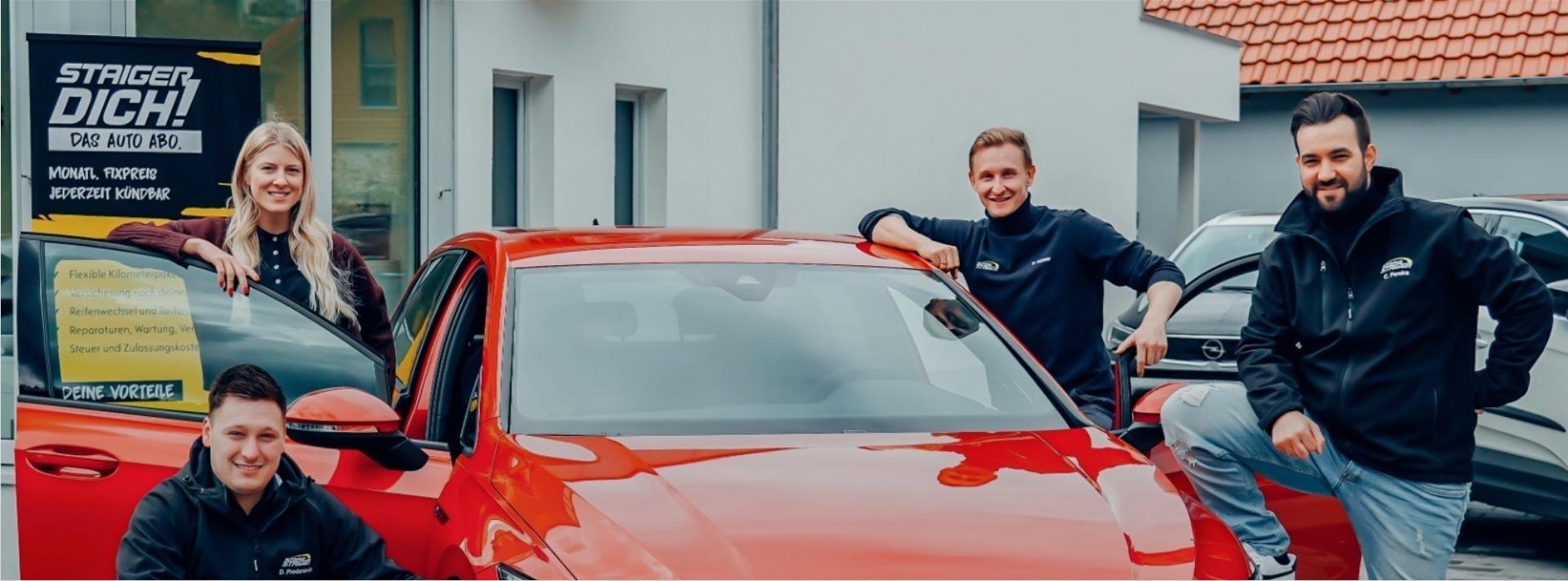 header-staiger-dich-team-neben-rotem-vw